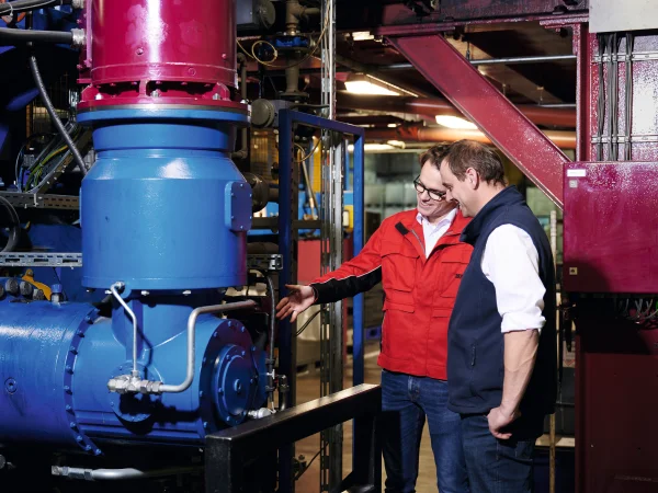 blau lackierte Anlage mit roter Antriebstechnik und zwei Männern