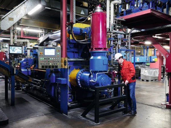 blau lackierte Anlage mit roter Antriebstechnik und Mann mit roter Jacke und weißem Helm