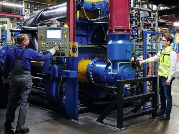 blau lackierte Anlage mit roter Antriebstechnik und zwei Männern